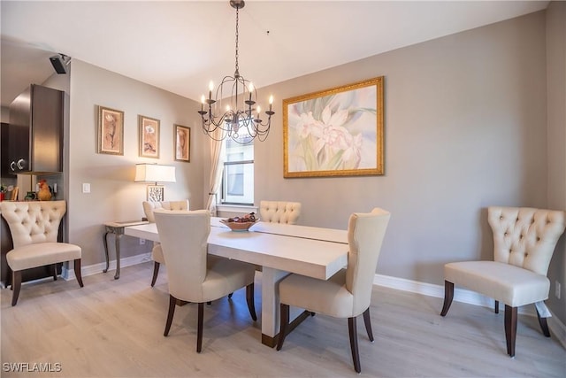 dining room featuring baseboards, light wood finished floors, and an inviting chandelier