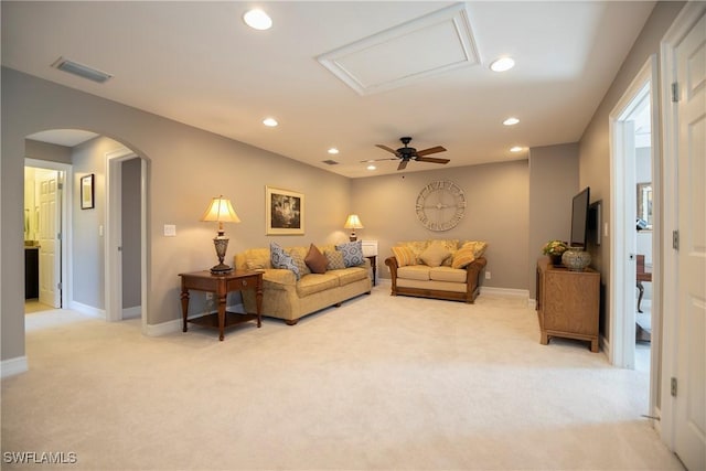 living room featuring arched walkways, recessed lighting, light colored carpet, visible vents, and baseboards