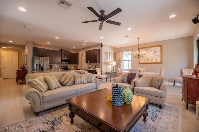 living room featuring light wood-type flooring, arched walkways, visible vents, and recessed lighting