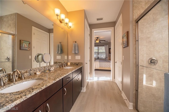 bathroom with visible vents, connected bathroom, a sink, a tile shower, and wood finished floors