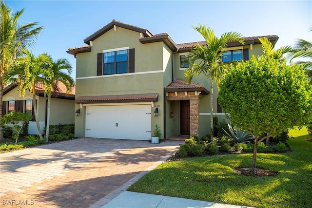 view of front facade featuring a tile roof, an attached garage, decorative driveway, a front lawn, and stucco siding