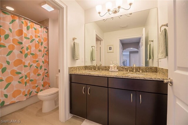 bathroom featuring a shower with shower curtain, a sink, toilet, and double vanity