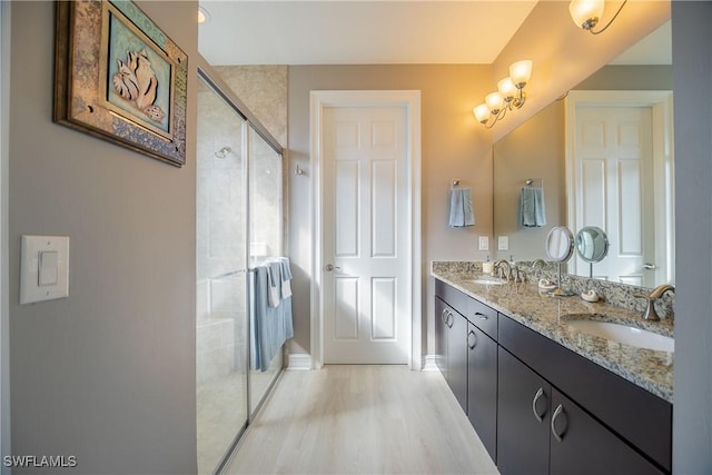 full bathroom featuring double vanity, a stall shower, a sink, and wood finished floors