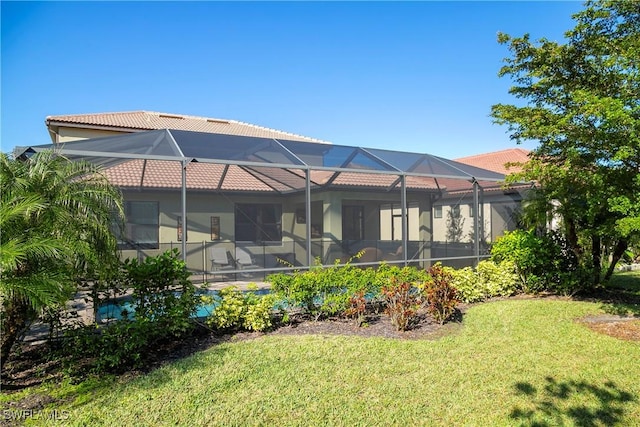 back of house featuring glass enclosure, a lawn, and a tiled roof