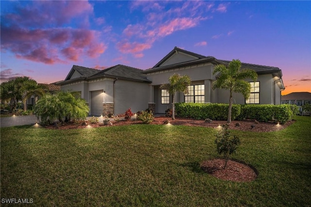 view of front of home featuring a garage, a yard, driveway, and stucco siding