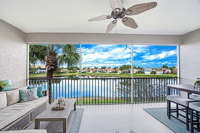 sunroom featuring a water view and a ceiling fan