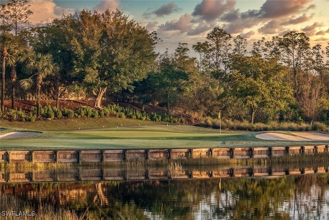 view of community with view of golf course, a water view, and a yard