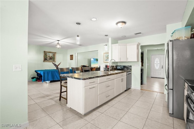 kitchen featuring a breakfast bar, stainless steel appliances, white cabinets, a sink, and a peninsula