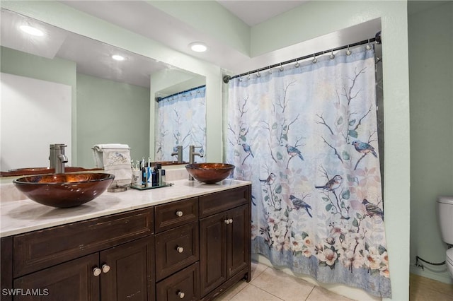 bathroom with double vanity, tile patterned flooring, a sink, and toilet