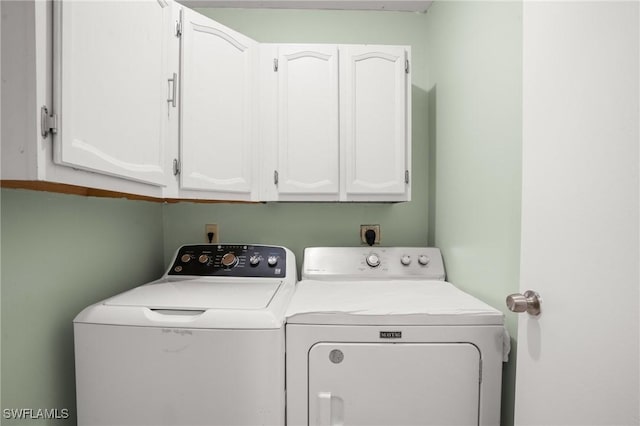 clothes washing area featuring washing machine and clothes dryer and cabinet space