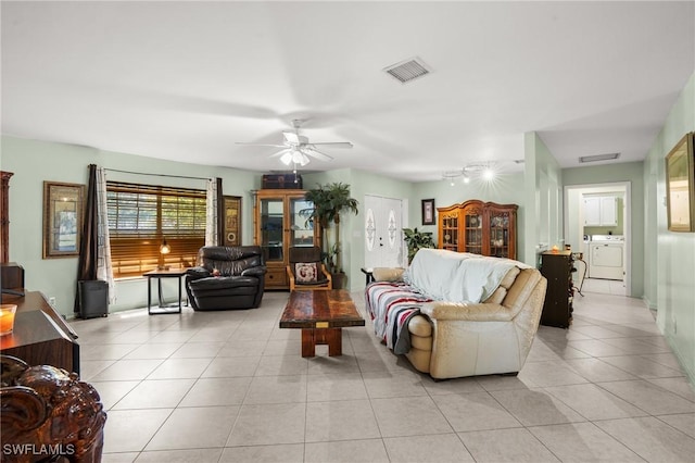 living room with light tile patterned floors, ceiling fan, washer / dryer, and visible vents