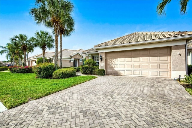 single story home with stucco siding, decorative driveway, a front lawn, a tile roof, and a garage