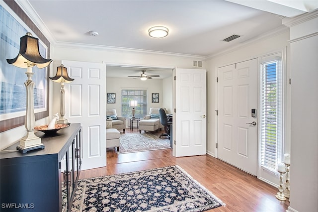 foyer with crown molding, visible vents, a ceiling fan, and wood finished floors