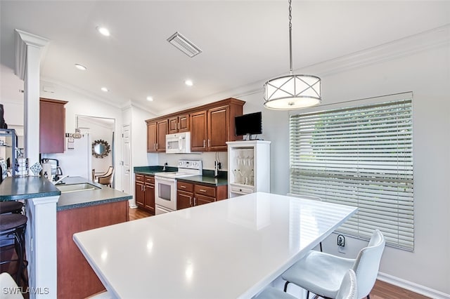 kitchen featuring lofted ceiling, white appliances, decorative light fixtures, dark countertops, and visible vents