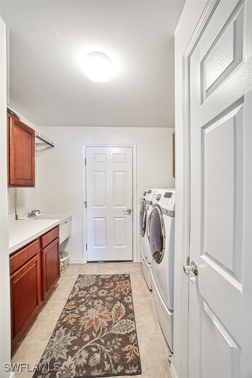 laundry area with washing machine and dryer, light tile patterned floors, and cabinet space