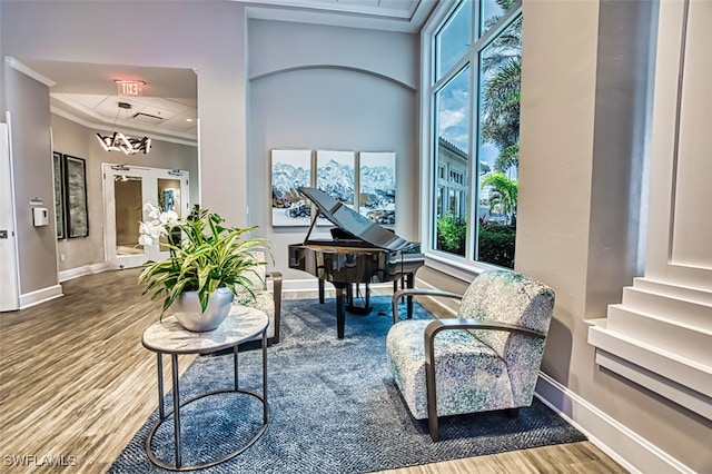 living area with baseboards, wood finished floors, and ornamental molding