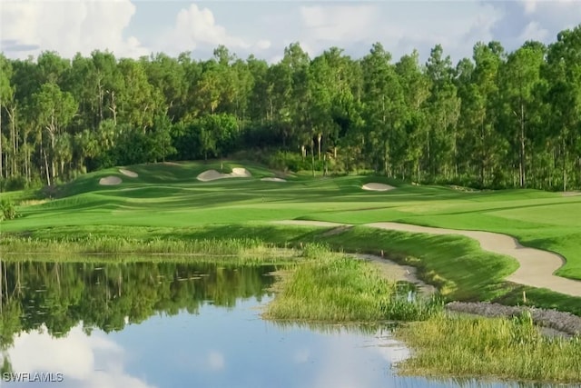 view of home's community with a wooded view, view of golf course, and a water view