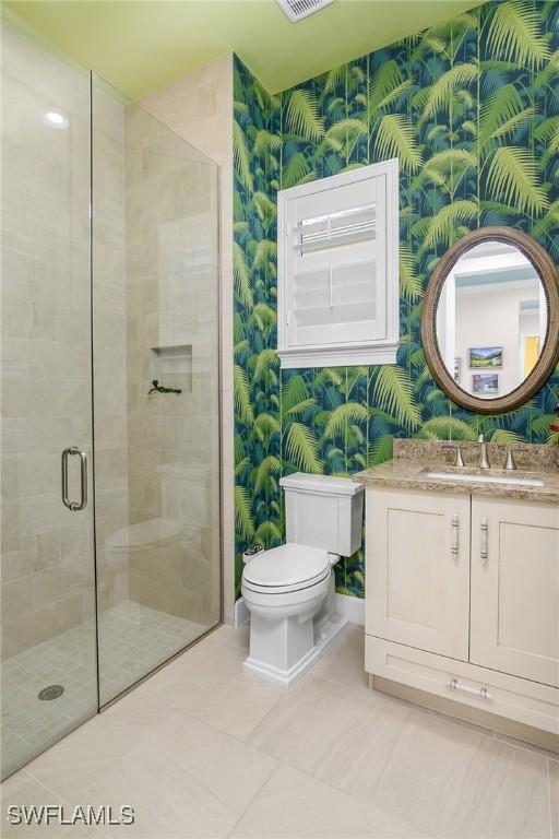 bathroom with tile patterned floors, vanity, toilet, and walk in shower