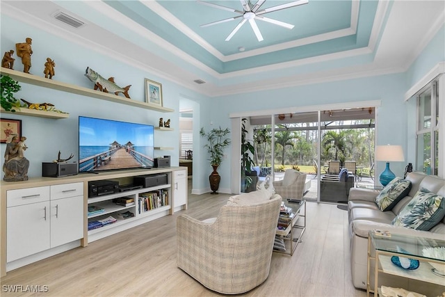 living room featuring ceiling fan, light wood-type flooring, crown molding, and a raised ceiling