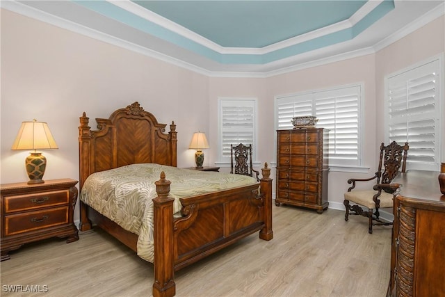 bedroom with a raised ceiling, light hardwood / wood-style floors, and ornamental molding