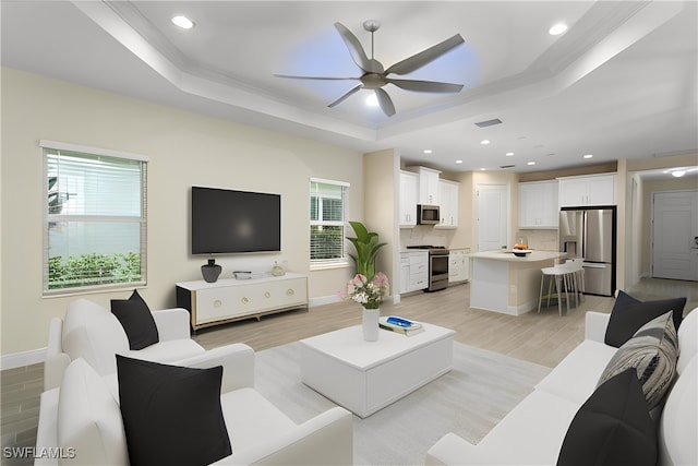 living room with a tray ceiling, light hardwood / wood-style flooring, and ceiling fan