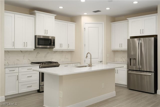 kitchen featuring a center island with sink, stainless steel appliances, and white cabinets