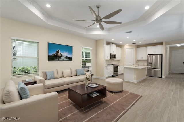 living room featuring a tray ceiling, crown molding, and light hardwood / wood-style floors