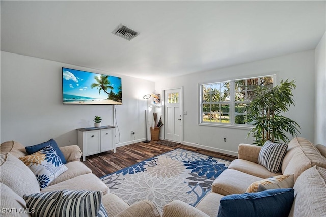 living area with dark wood-type flooring, visible vents, and baseboards