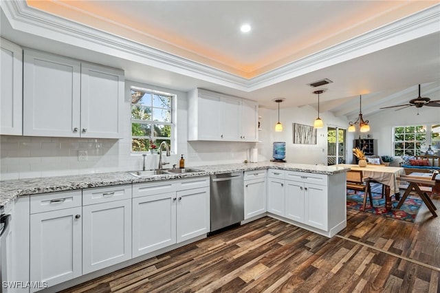 kitchen with white cabinets, dishwasher, a peninsula, a tray ceiling, and a sink