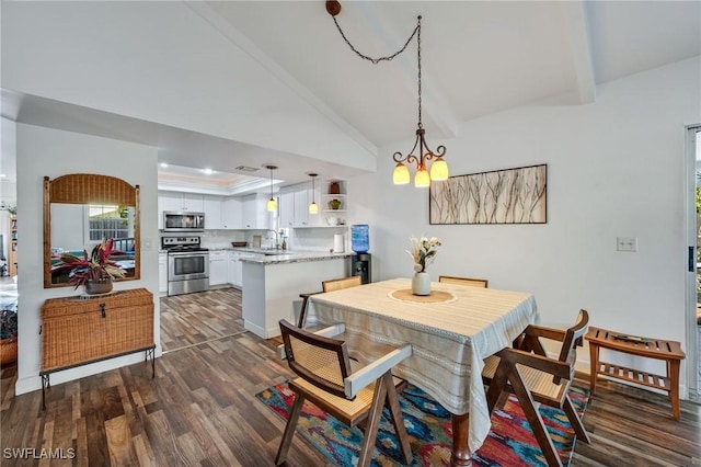 dining space featuring lofted ceiling, a tray ceiling, dark wood-type flooring, and a notable chandelier