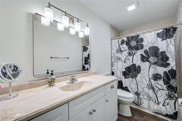 full bathroom with wood finished floors, curtained shower, vanity, and toilet