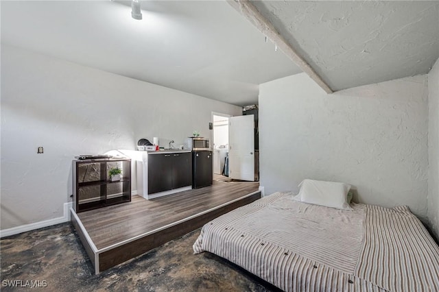 bedroom featuring unfinished concrete floors, baseboards, vaulted ceiling, and a textured wall