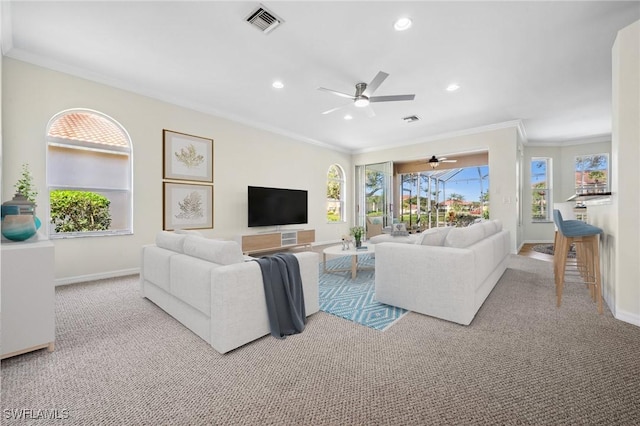 living area with ornamental molding, a healthy amount of sunlight, visible vents, and baseboards