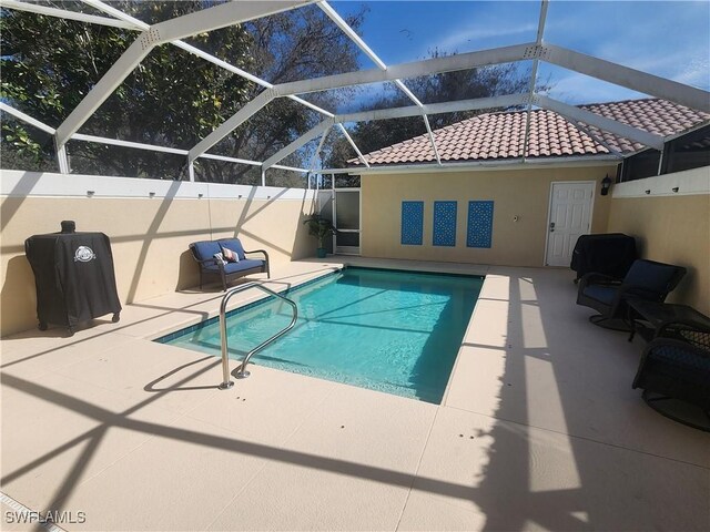 view of swimming pool featuring glass enclosure, a fenced in pool, and a patio