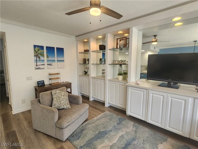 living room with a ceiling fan, ornamental molding, dark wood finished floors, and baseboards