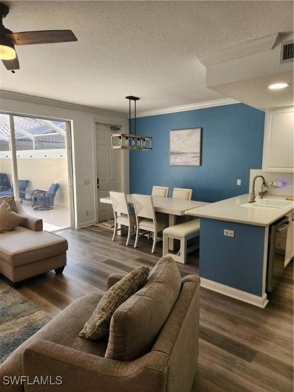 living room with crown molding, dark wood-type flooring, baseboards, ceiling fan, and a textured ceiling