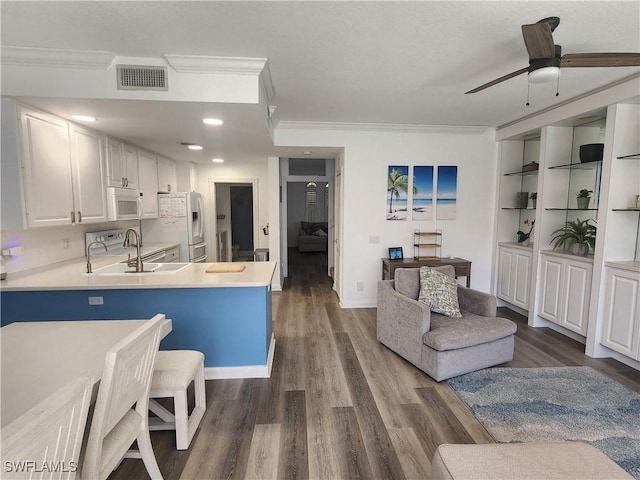 kitchen featuring white appliances, crown molding, wood finished floors, light countertops, and ceiling fan