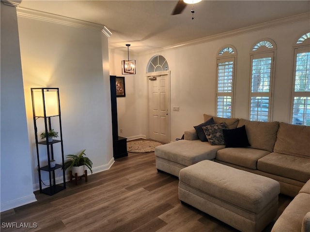 living area featuring dark wood finished floors, ornamental molding, baseboards, a chandelier, and a ceiling fan