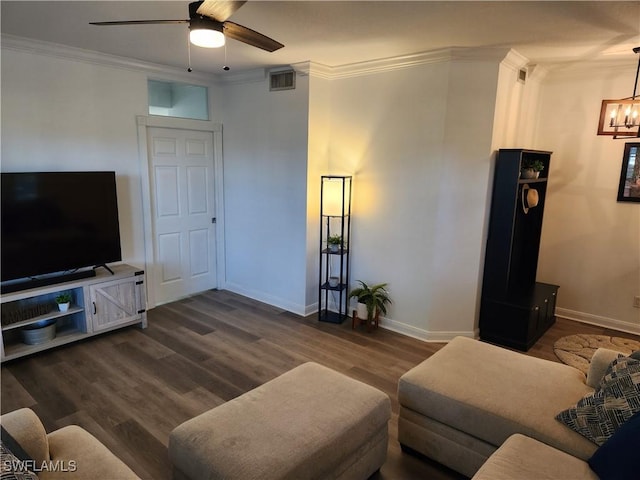 living area featuring a ceiling fan, ornamental molding, dark wood-style flooring, a chandelier, and baseboards