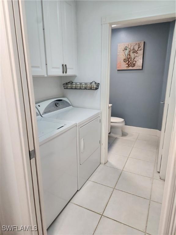 laundry room featuring independent washer and dryer, light tile patterned floors, and cabinet space