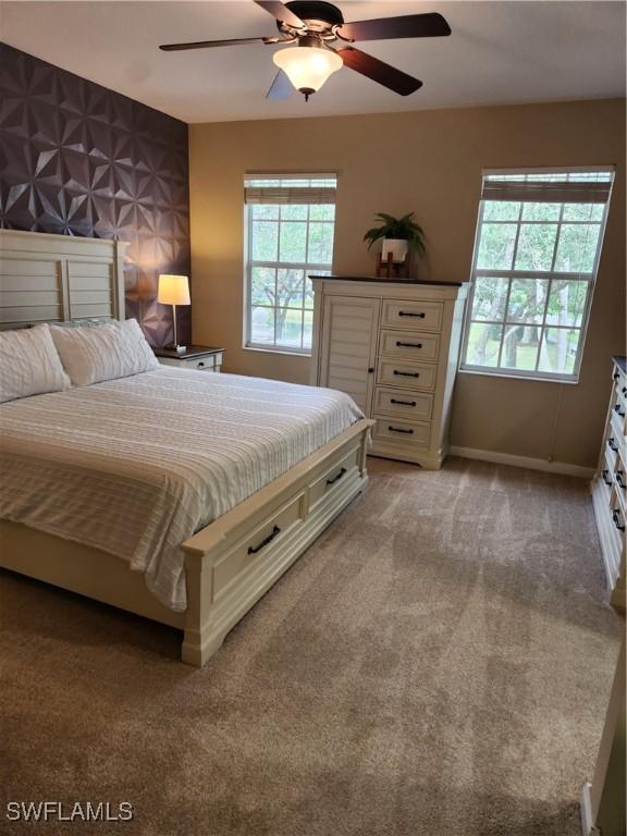 bedroom with multiple windows, light colored carpet, and ceiling fan