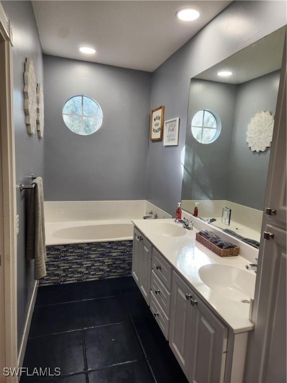 bathroom featuring tile patterned floors, a bath, double vanity, and recessed lighting