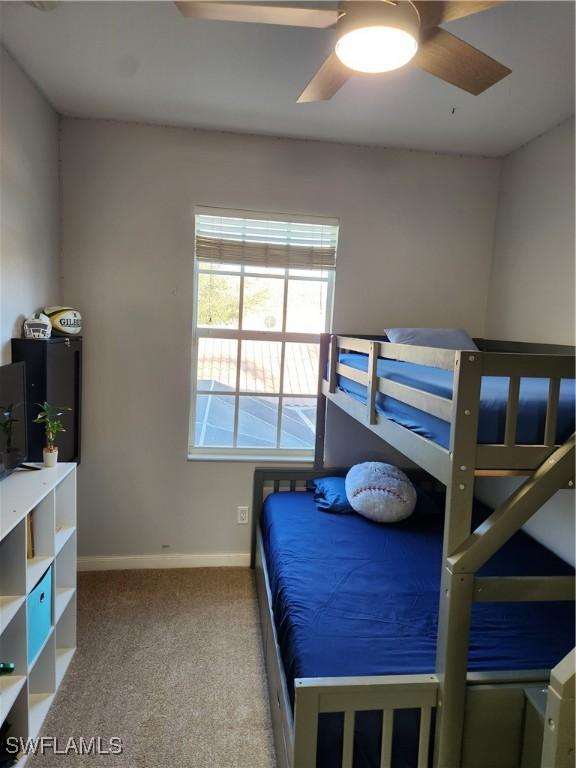 carpeted bedroom featuring baseboards and a ceiling fan