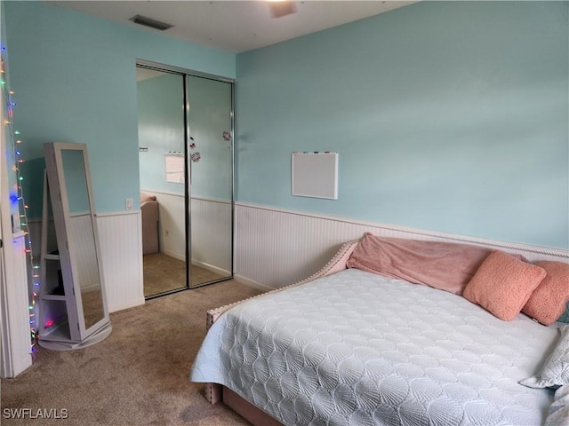 bedroom featuring wainscoting, carpet, and a closet