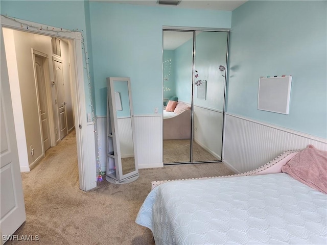 bedroom with carpet flooring, a closet, and a wainscoted wall