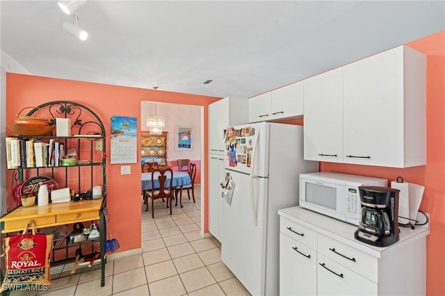 kitchen with white appliances, an inviting chandelier, white cabinets, light countertops, and light tile patterned floors