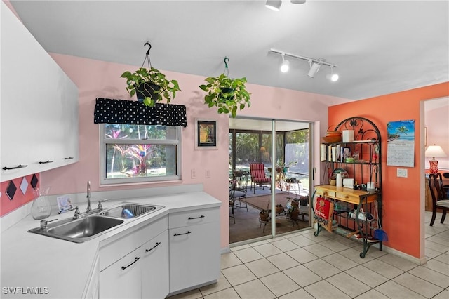 kitchen with light tile patterned flooring, a sink, light countertops, white cabinets, and track lighting