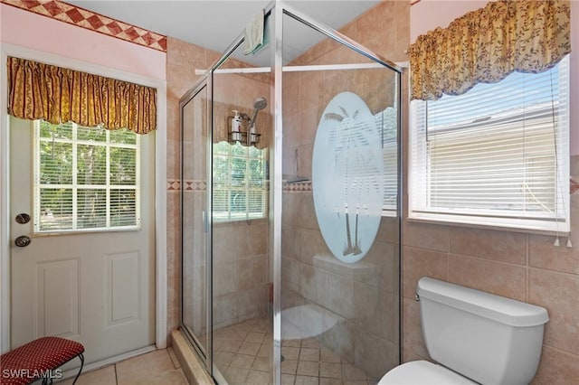 full bathroom with tile patterned flooring, tile walls, toilet, and a stall shower