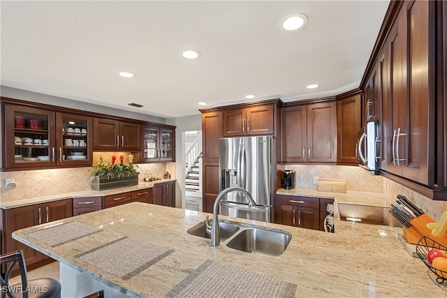 kitchen with a breakfast bar, stainless steel appliances, light stone counters, and sink