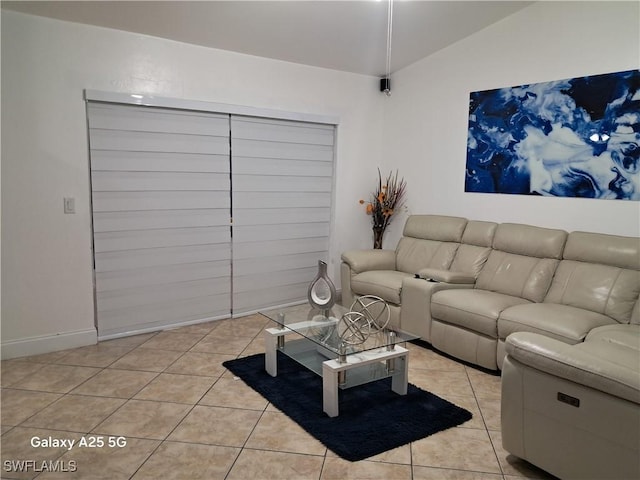 living room with lofted ceiling, light tile patterned flooring, and baseboards